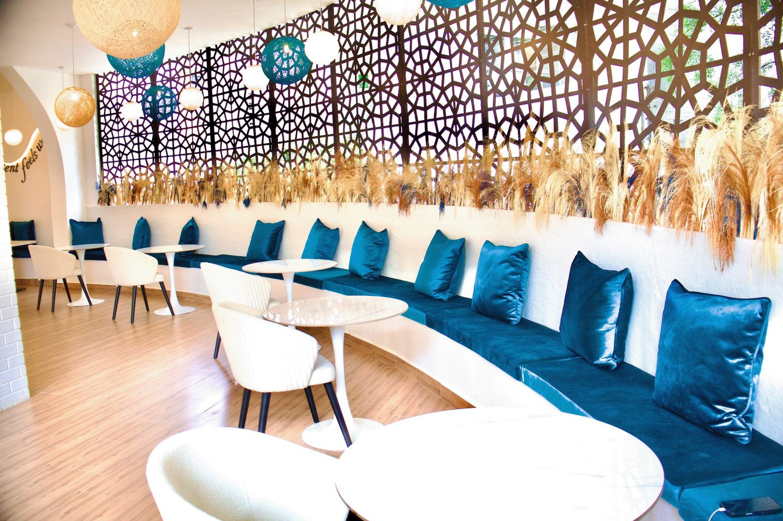 Café Naimora window banquette with blue velvet cushions, pampas grass and the patterned screen