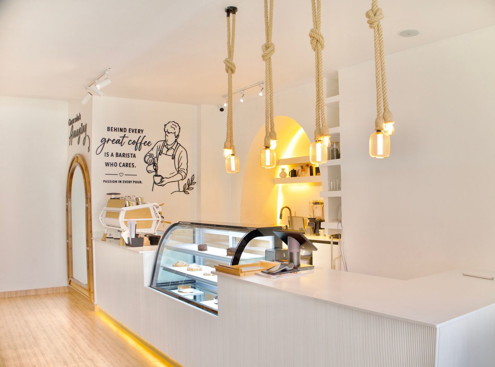 Café Naimora counter with the pastry display, rope pendant lights and the barista wall art