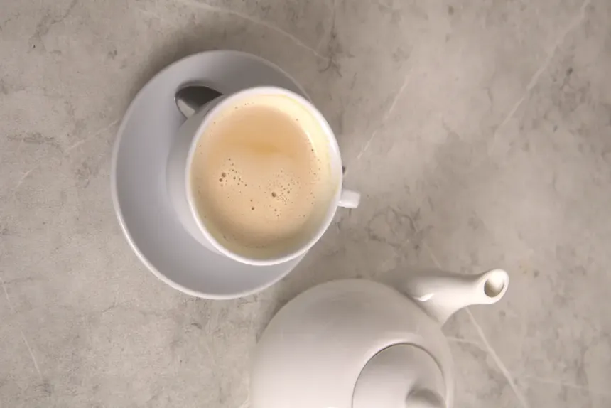 Somali tea in a white cup beside a teapot